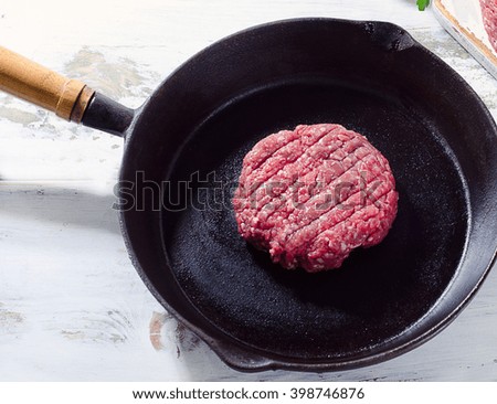 Raw beef burger patty on pan. Top view