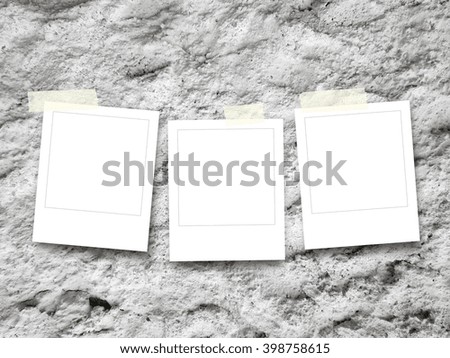 Close-up of three square blank instant photo frames with adhesive tape on weathered rough wall background