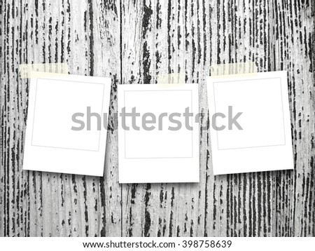 Close-up of three square blank instant photo frames with adhesive tape on weathered wooden boards background