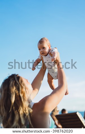 young woman with her baby on the beach during sunset . Mother with her baby on the beach watching the sunset.