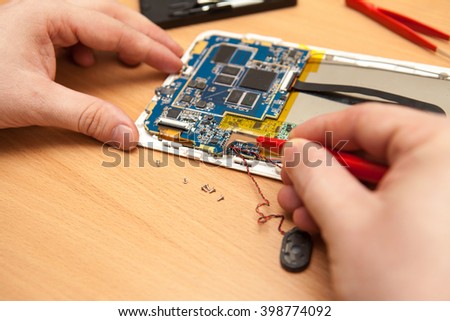 master repair the tablet PC. Hands of a top view. Royalty-Free Stock Photo #398774092