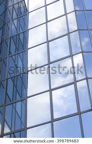 glass and steel office facade reflects clouds and blue sky