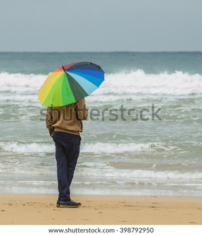 Man with colorful umbrella oceanfront