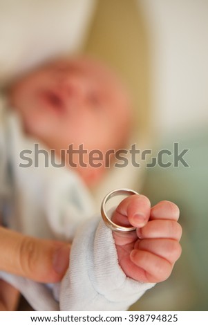 Baby hand. Closeup of baby hand with ring . Family concept with the wedding ring in baby finger. Selective focus. Royalty-Free Stock Photo #398794825