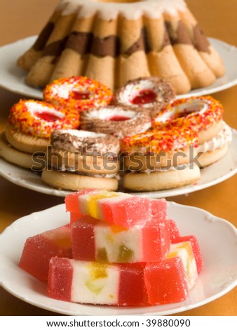 Plates with fruit candies, cookies and biscuit pie. Shallow DOF.