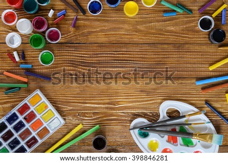 Paint, pencils on the wooden table with blanked space