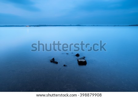 Long exposure seascape during blue hour sunset with rocks and roots as foreground. Nature composition
