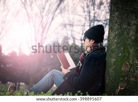 asia man reading a book under big  tree