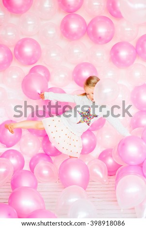 little girl with blond hair playing with pink and beige balloons. Happy Birthday