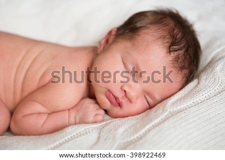 picture of a newborn baby curled up sleeping on a blanket
