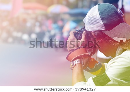 Photographer taking photo with professional digital camera outdoors, people shopping at market street in sunny day, blur background with bokeh, filtered with retro colors