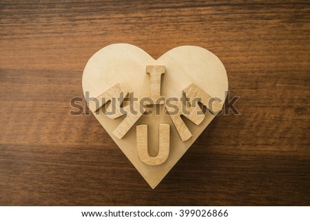 Happy Mothers day. I Love my mum Concept. Wood heart and Wooden letters spelling. Image with shadows on table.