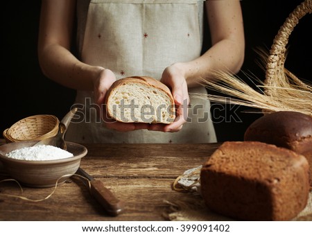 Baker woman holding homemade rustic wheat bread in hands. Selective focus.