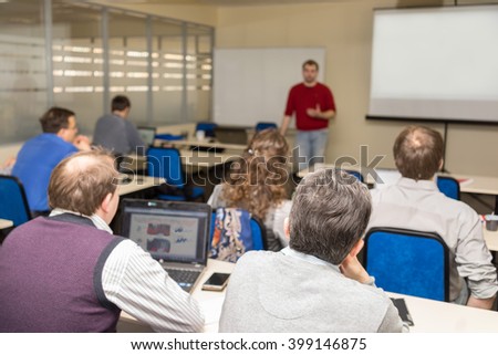 The audience listens to the acting in a conference hall. Focus is under the man on the front ground Royalty-Free Stock Photo #399146875