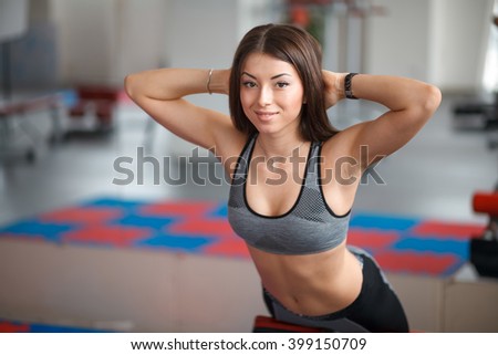 Beautiful young girl engaged in fitness in the gym. Performs physical exercises on the press.
