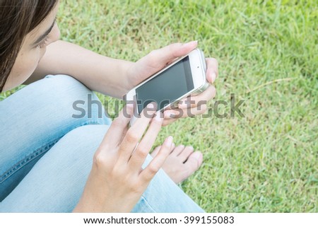 Woman sitting in the park with mobile phone in her hand