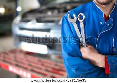 Hand of car mechanic with wrench. Auto repair garage. Royalty-Free Stock Photo #399175633
