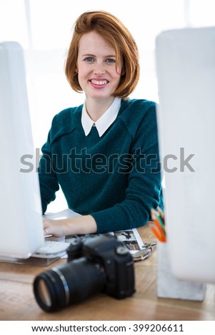 smiling hipster photographer, sitting at her desk, on her computer