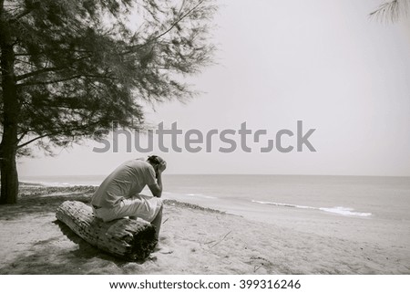 Sad Young Man sit on the old wood with Beach background