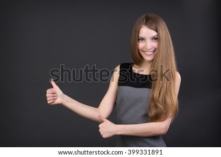 beautiful smiling girl holding thumbs up, studio picture