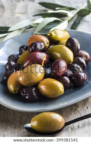 Mixed olives on a plate with a spoon an olive leaves