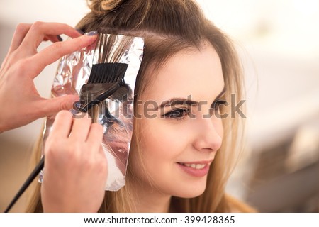 Professional hairdresser dyeing hair of her client Royalty-Free Stock Photo #399428365