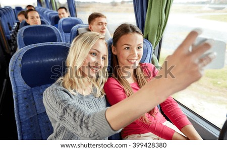 transport, tourism, road trip and people concept - happy young women or friends in travel bus taking selfie by smartphone