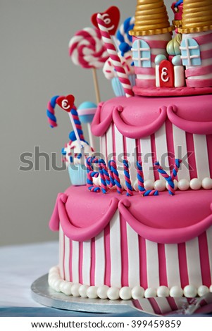 A fancy birthday cake with a candyland theme. The three layer cake is covered with fondant and candy decorations