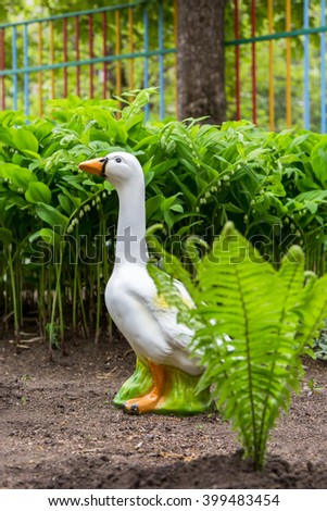 Garden figure of a goose and lilies of the valley