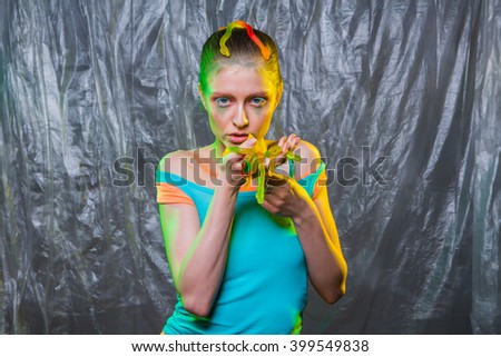 Young woman with colorful make up holds gummy jelly worms candies in hands.