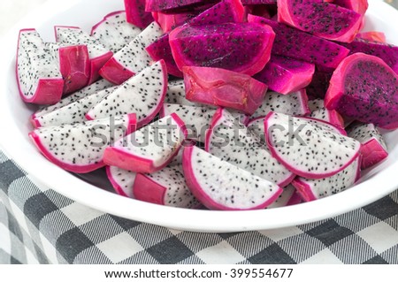 Beautiful fresh ripe Sliced red and white dragon fruit on the white plate and fabric pattern background