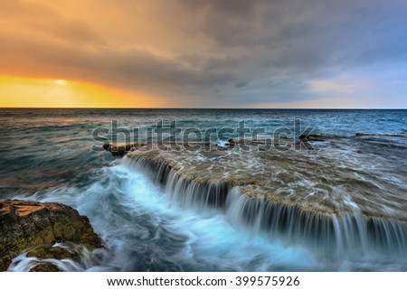 At sunrise, many large waves struck the ancient coral rock coast at HangRai( Otter Cave) in the conservation area of the National Park mountain of God, creating a waterfall in the ocean
 