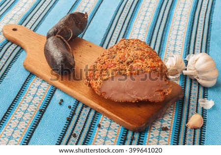 A piece of meat balyk with a crust of spices and sesame seeds on a cutting board