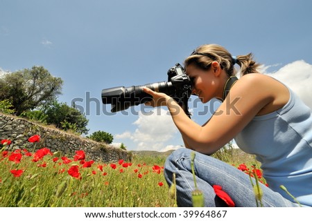 professional woman photographer in a field with poppies in spring