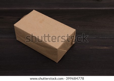 brown craft paper box on black rough wooden table close up photo, copy space