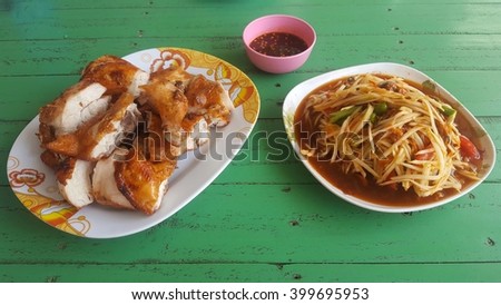 Thai food papaya salad spicy with Sticky rice ,roasting chicken and fresh cabbage  in green wooden table