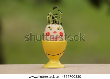 Sunflower sprouts in decorated egg like a clown