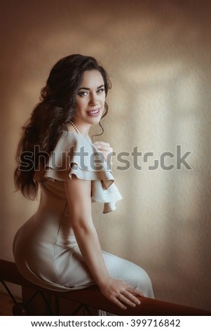 Beautiful woman in the beige dress in the bedroom