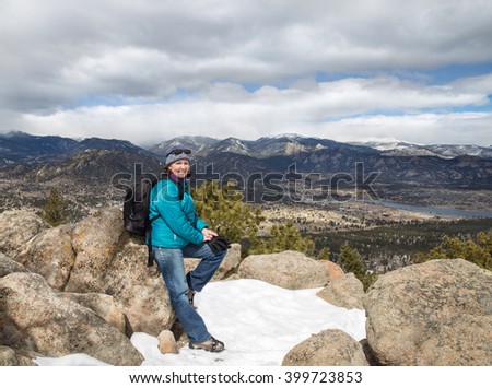 horizontal orientation color image of a happy, smiling, woman hiker with spectacular views of the Rocky Mountains in the background/ Winter Hiker at 9,000 feet