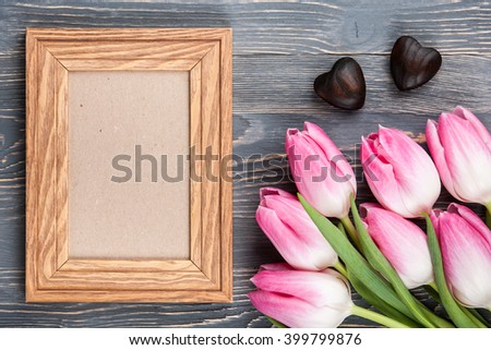 Fresh pink tulips and blank wooden frame