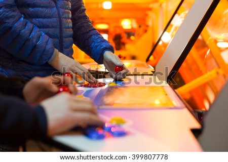 Detail of players hands interacting and playing with joysticks and buttons on an old arcade game in a gaming room Royalty-Free Stock Photo #399807778