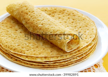 Plate of crepes, over yellow background.
