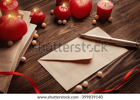 Gift card for Valentine's Day with pen and candles on wooden background