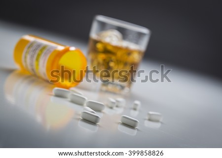Several Prescription Drugs Spilled From Fallen Bottle Near Glass of Alcohol. Royalty-Free Stock Photo #399858826