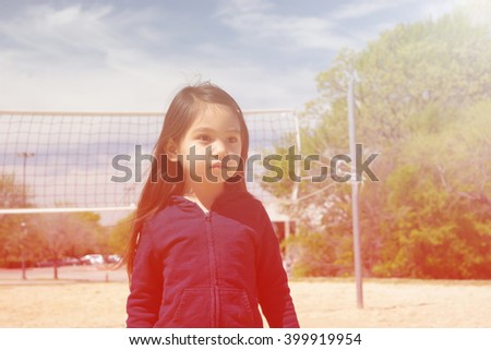 A closed up of lovely little girl standing still  at public park with volleyball net and blue sky background,filtered color tone in picture