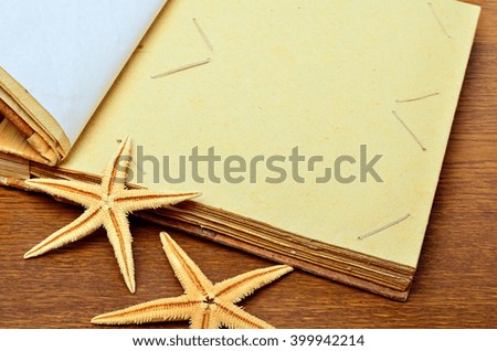 Vintage book or photo album with empty photo frames and starfish on wooden background.