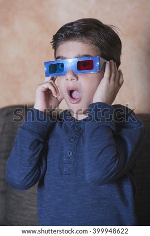 Little boy reacts while watching a 3D movie. Vintage effect image with shallow depth of field
