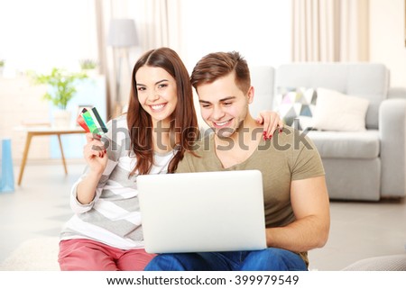 Young couple doing online shopping with laptop and credit card in room
