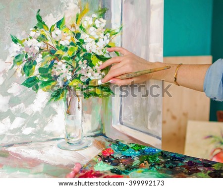 Brush and oil paints on a palette, paint a picture of the artist's hands, texture mix paint in different colors. Artist holding a palette with paint, brushes and palette knife