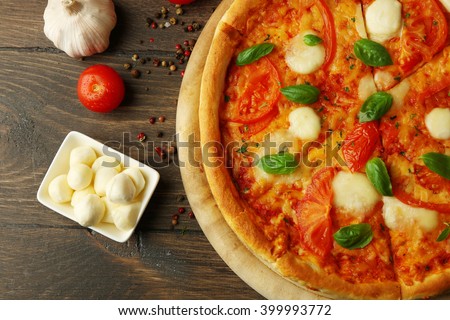 Margherita pizza with tomatoes, garlic, spices and Mozzarella on wooden background